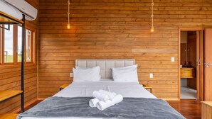 A wooden-paneled bedroom with a bed, pillows, and a bedside table. - Apt w/ Fireplace, Jacuzzi, and Amazing View Vst027 (Anitapolis)