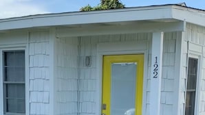 A single-story house with a yellow door and a number '122' on the right side.