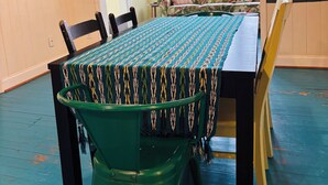 A dining area with a table covered by a patterned tablecloth, surrounded by chairs.