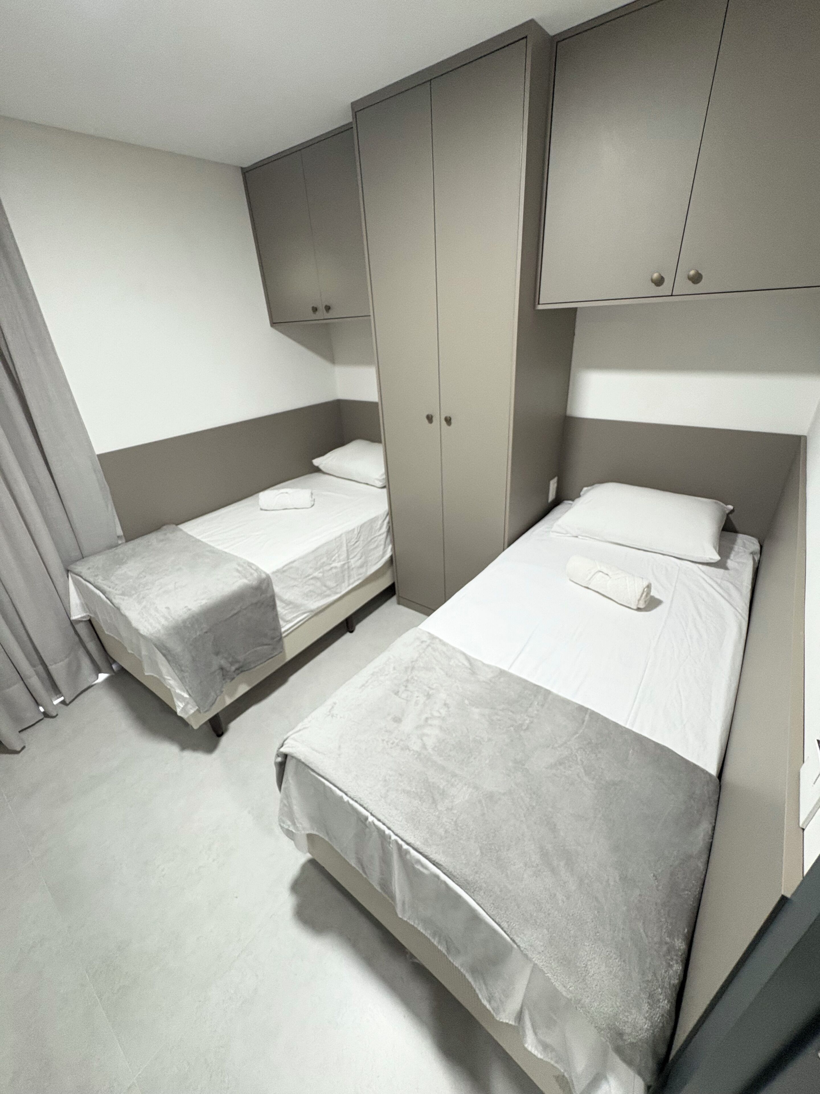 Habitación doble con dos camas individuales, cabeceros grises y un armario.