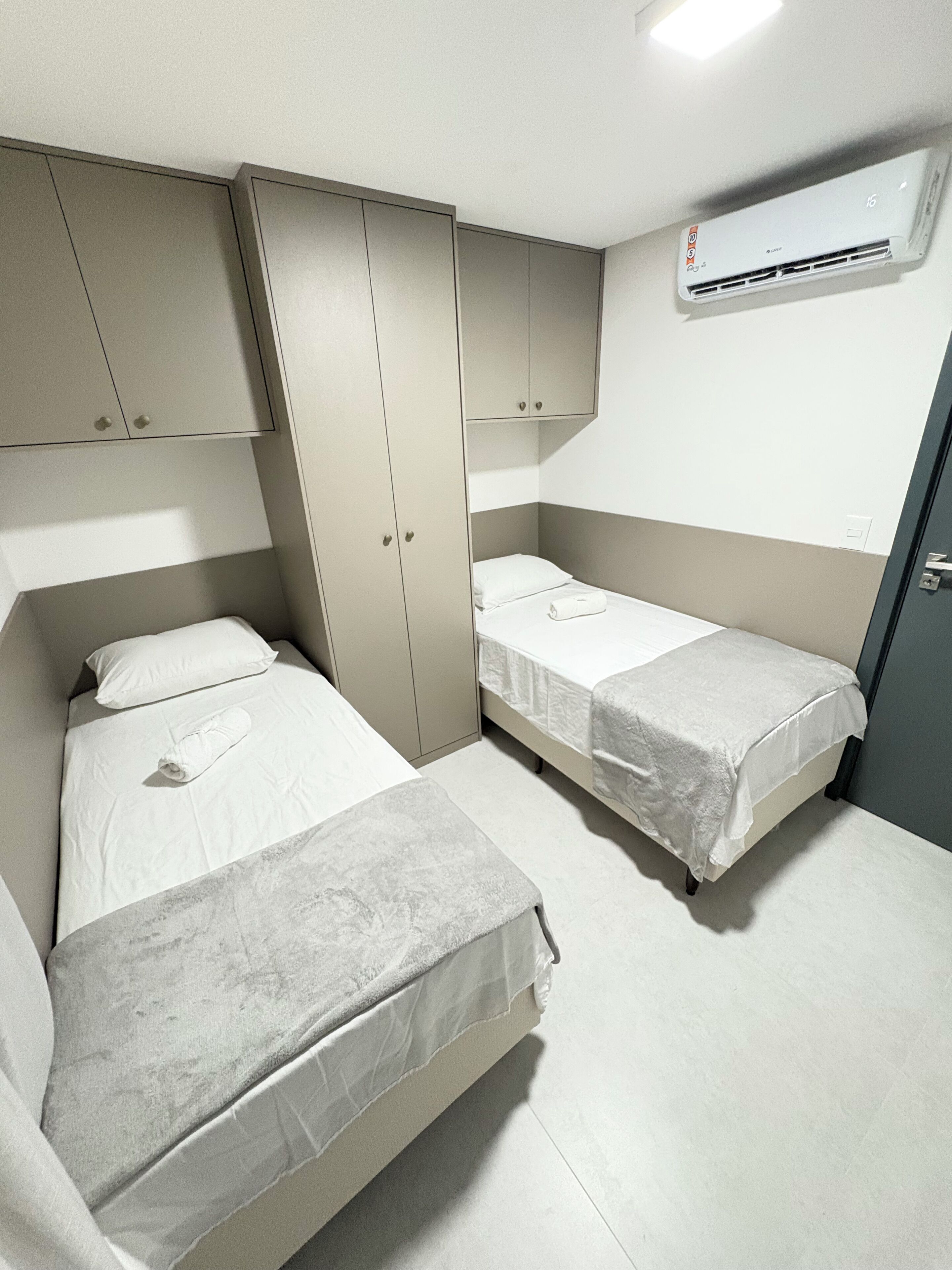 Habitació d'hotel senzilla i compacta, amb dos llits individuals, un armari i aire condicionat.