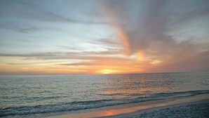 A beach scene with a sunset over the ocean. - Tranquil OASIS (Sarasota)