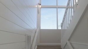 A staircase with white railings and wooden steps leading to a bright room with large windows. - Tranquil OASIS (Sarasota)
