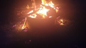 Fogueira com chamas e brasas, em um ambiente escuro.