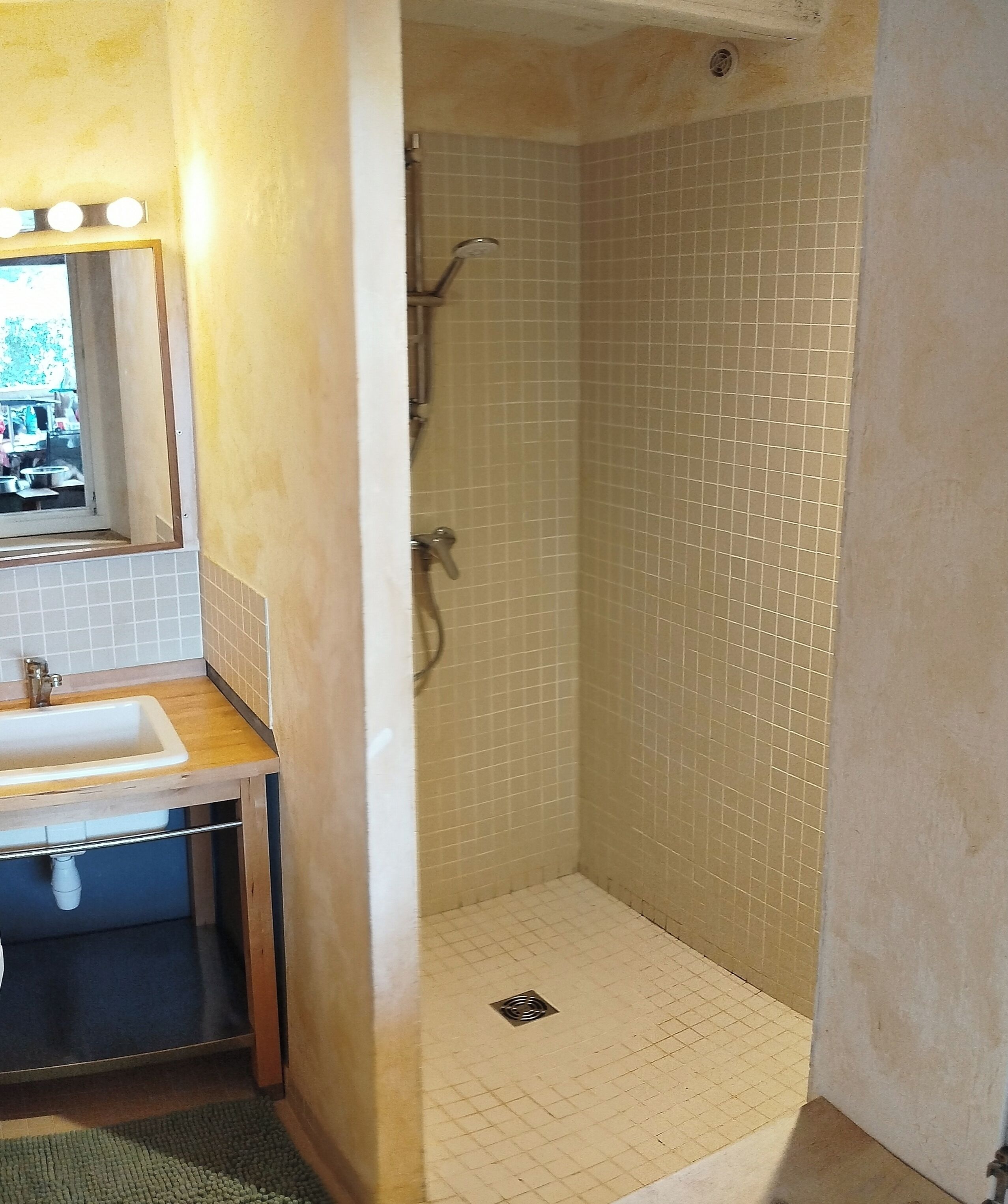 A bathroom with a sink, mirror, and shower.