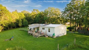 A single-story house with a porch, a small deck, and a fenced yard. - 3BR Home Near Snowshoe | Tesla | Pet Friendly  | Elk Mountain Apres’ (Marlinton)
