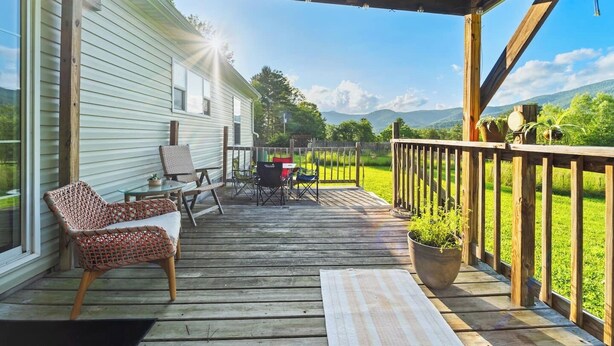A wooden deck with outdoor furniture, a covered area, and a view of a green landscape. - 3BR Home Near Snowshoe | Tesla | Pet Friendly  | Elk Mountain Apres’ (Marlinton)
