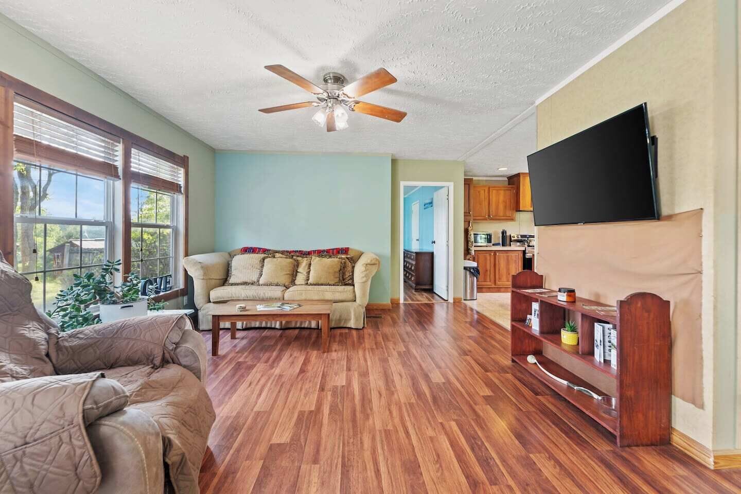 Spacious living room with smart TV streaming, a breezy ceiling fan, and an open-concept flow into the heart of the home.