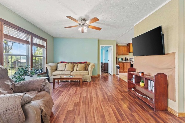 Spacious living room with smart TV streaming, a breezy ceiling fan, and an open-concept flow into the heart of the home.