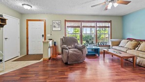 A living room with a wooden floor, a ceiling fan, a sofa, a coffee table, and a chair. - 3BR Home Near Snowshoe | Tesla | Pet Friendly  | Elk Mountain Apres’ (Marlinton)