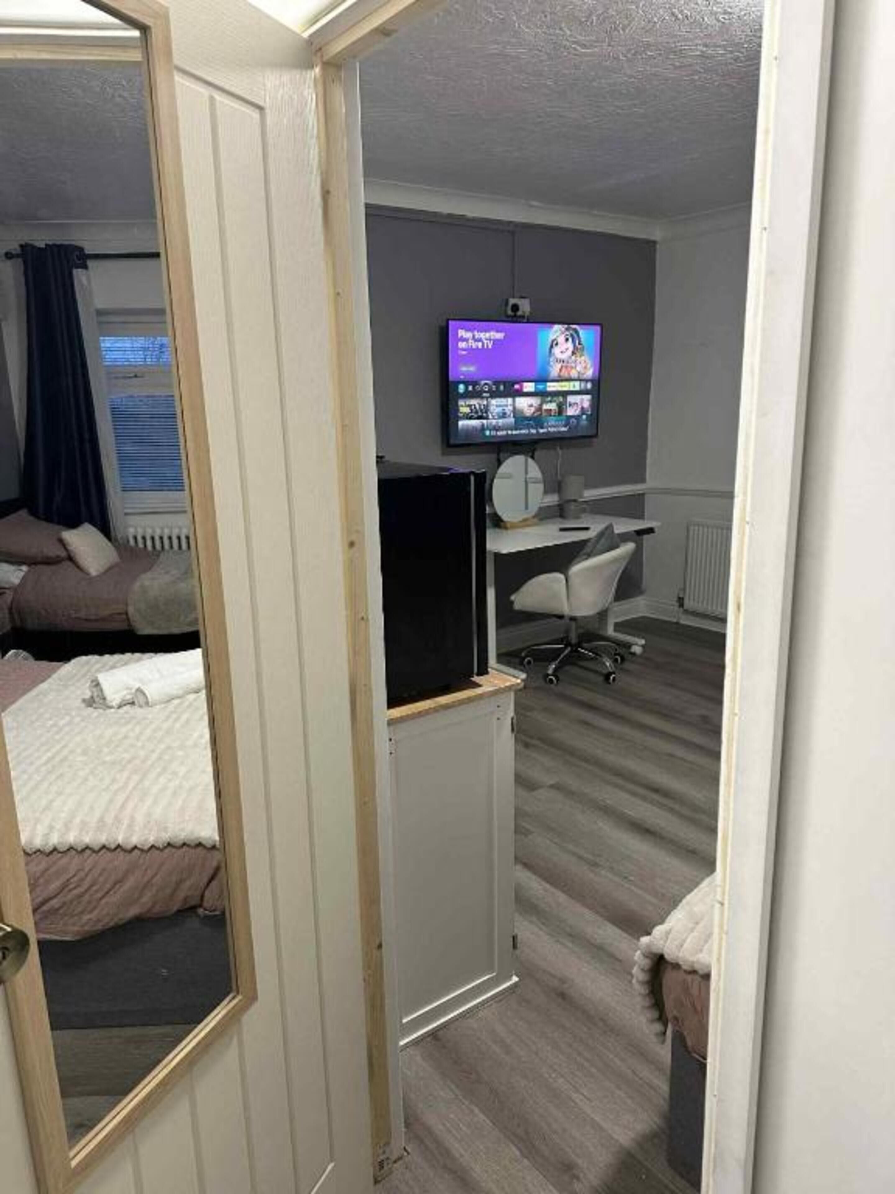 Ein Hotelzimmer mit Bett, Schreibtisch, Stuhl, Fernseher und einem Fenster mit Vorhängen.