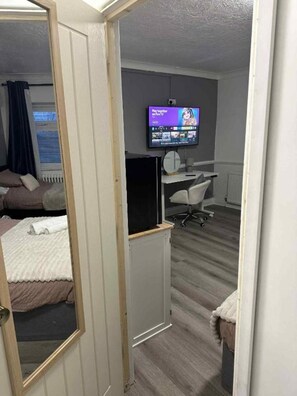 A hotel room with a bed, a desk, a chair, a TV, and a window with curtains. - OYO Prince of Wales Country Hotel (Princetown)