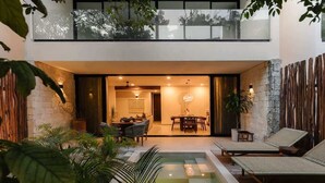 A modern outdoor living area with a pool, lounge chairs, and a dining setup. - Makech Samsara Tropical Beach Club Access (Tulum)