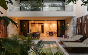 A modern outdoor living area with a pool, lounge chairs, and a dining setup.