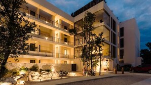 A multi-story hotel with balconies, outdoor seating, and a well-lit entrance. - Makech Samsara Tropical Beach Club Access (Tulum)