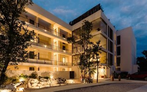 A multi-story hotel with balconies, outdoor seating, and a well-lit entrance.