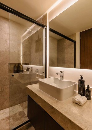 A modern bathroom with a large mirror, a rectangular sink, and a glass shower enclosure.