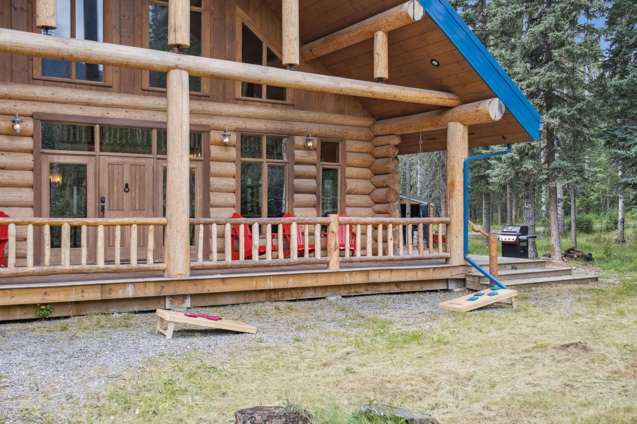 A log cabin with a porch, a grill, and a deck.