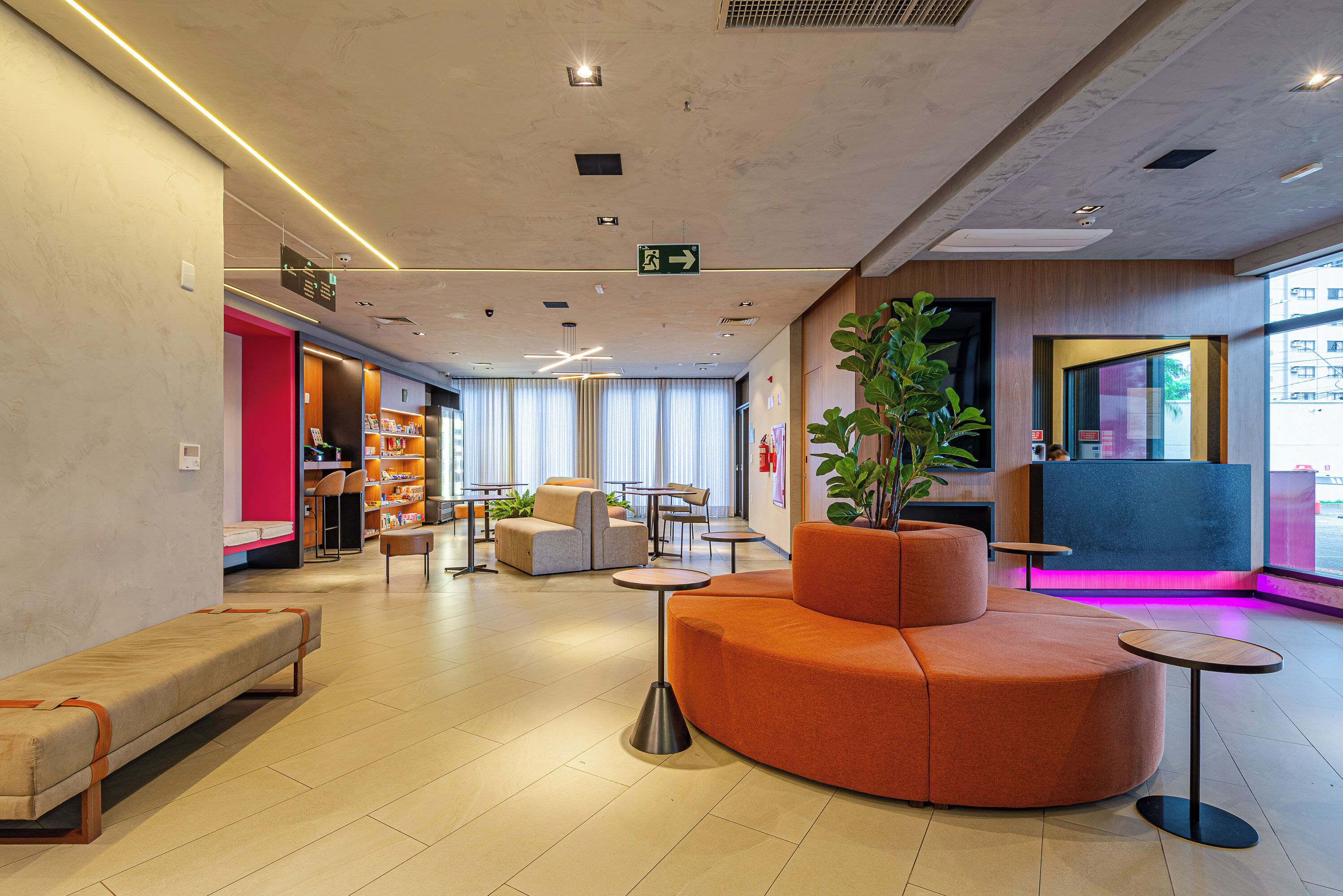 A modern lobby with a seating area, a reception desk, and a large window providing natural light.