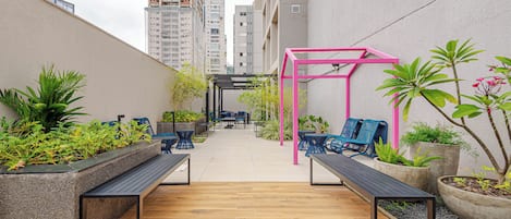 An outdoor patio with seating, planters, and a pink pergola structure.