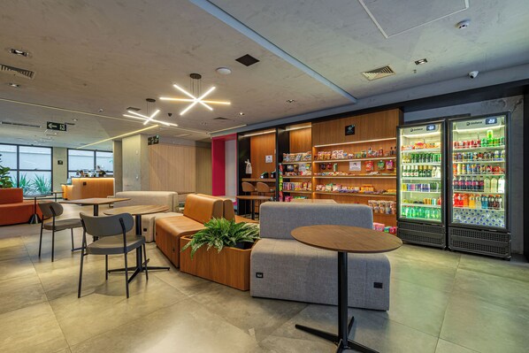 A modern lounge area with seating, a coffee station, and a snack bar with refrigerated drinks. - Roomo Transamerica Goiânia Marista Urbà (Goiania)