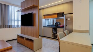 A modern hotel room with a TV, wooden entertainment unit, kitchenette, and seating area. - Roomo Transamerica Goiânia Marista Urbà (Goiania)