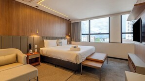 A modern hotel room with a large bed, a sofa, a desk, and a TV. - Roomo Transamerica Goiânia Marista Urbà (Goiania)