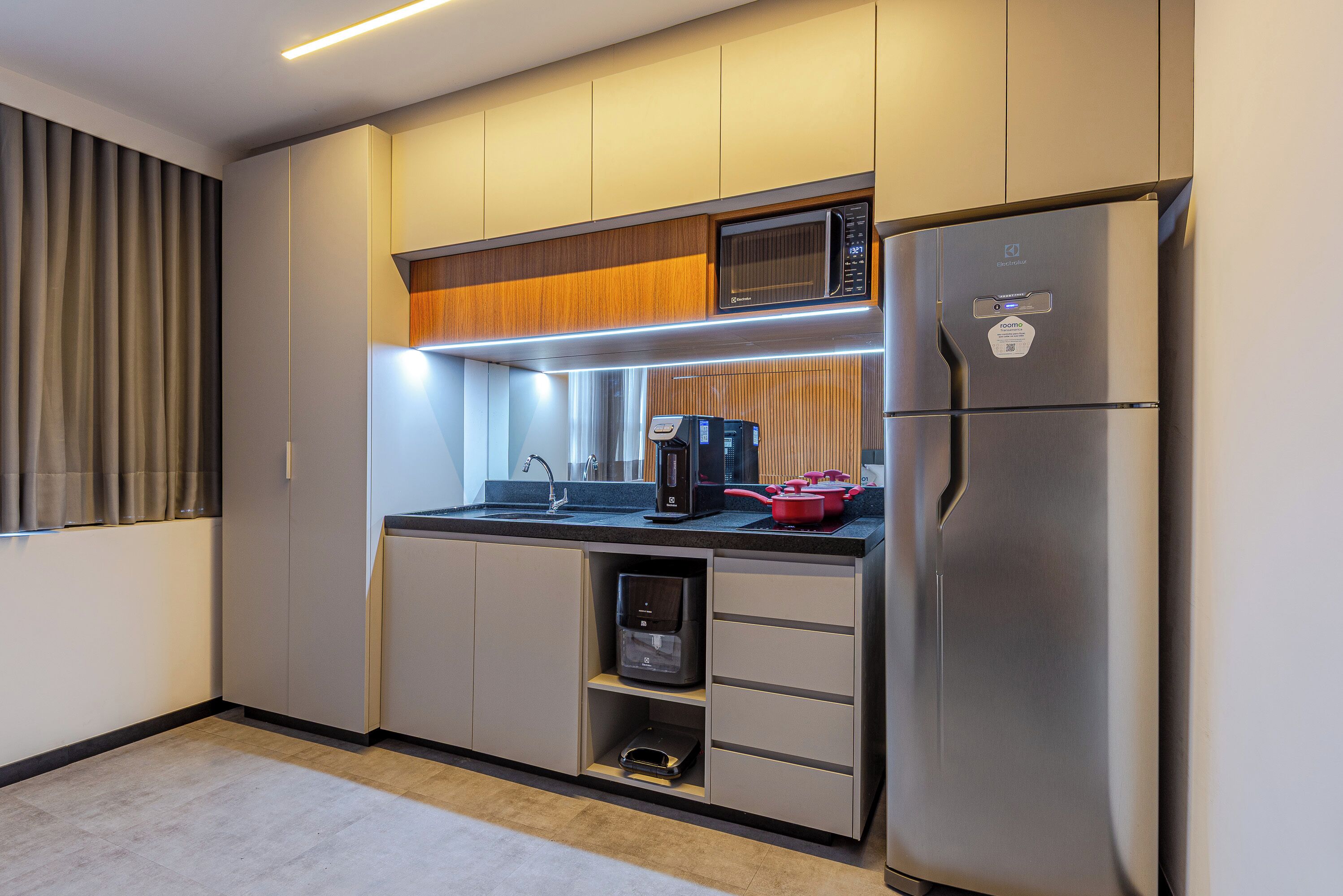 A modern kitchen with a built-in microwave, a coffee maker, and a refrigerator.