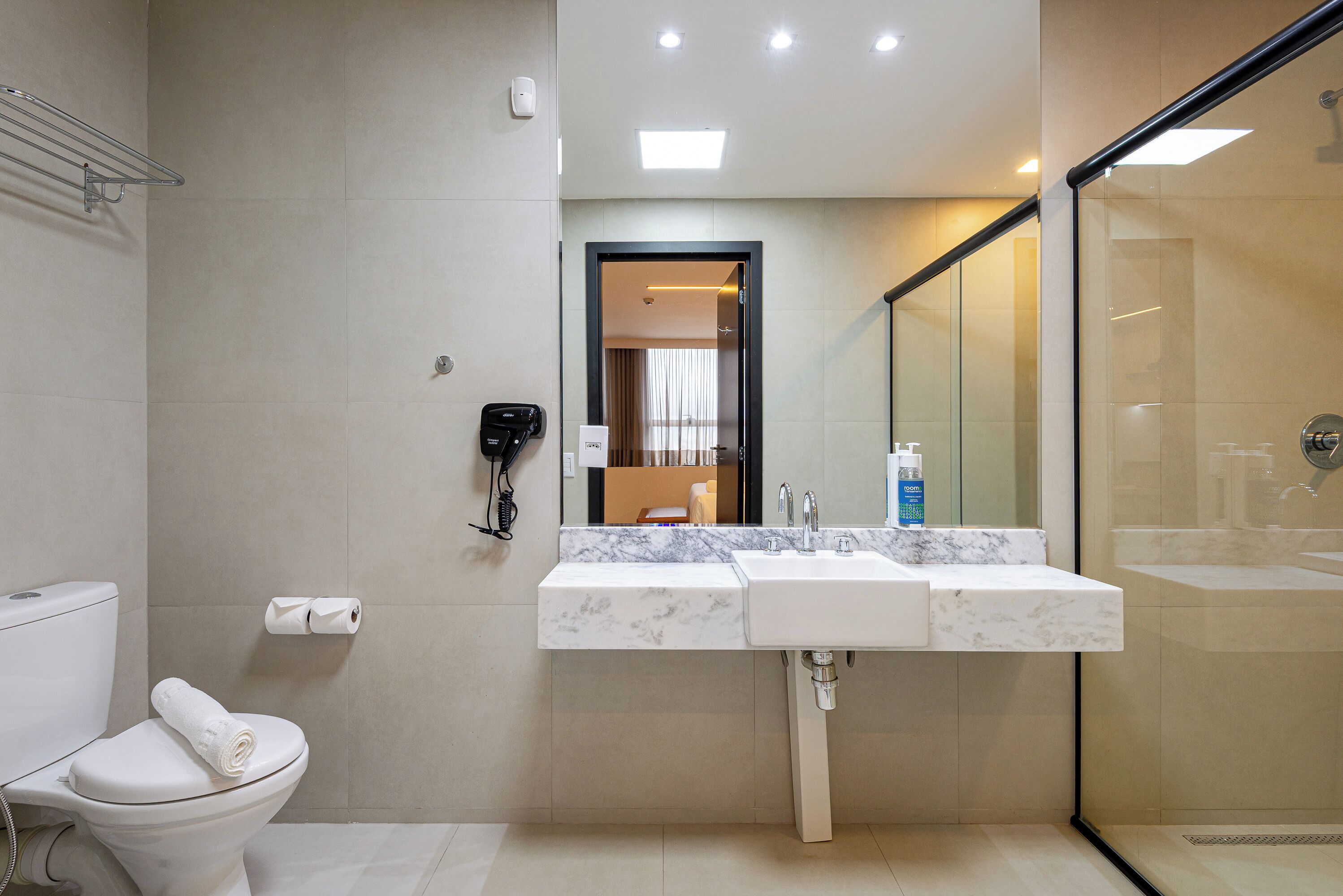Un baño moderno con inodoro, lavamanos con espejo y zona de ducha.