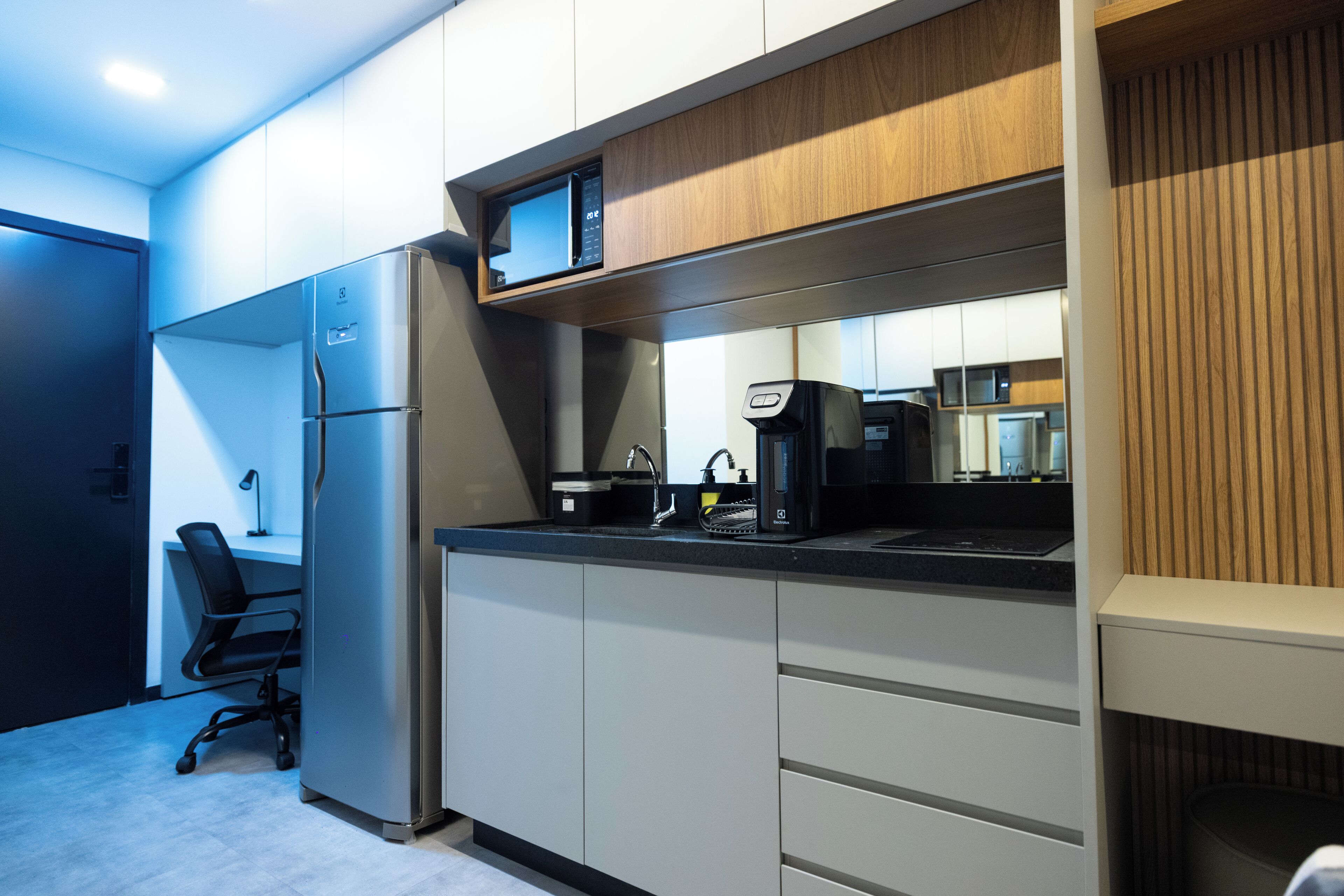 Een moderne keuken met een ingebouwde magnetron, koffiezetapparaat en een koelkast.