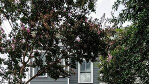 A two-story house with a front porch, a brick foundation, and a small garden area. - Bright & Modern 3BR | Walk to Dining and Park (Richmond)