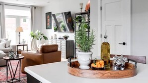 A modern living room with a sofa, coffee table, and decorative items including a plant and a tray with snacks. - Bright & Modern 3BR | Walk to Dining and Park (Richmond)