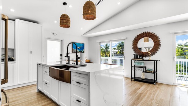 A spacious kitchen with white cabinetry, a large island, and a view of the outdoors.