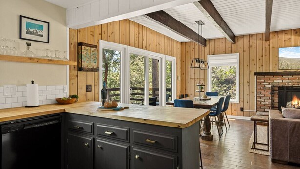 Una cocina con paneles de madera, una isla central y un comedor con chimenea.