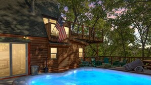 Una cabaña de madera con jacuzzi y sillas de terraza.