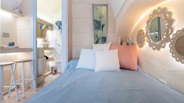 A bedroom with a bed, a desk, and a chair. There is a bathroom with a toilet and a sink. - Laggetto Corner (Otranto)