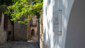 A narrow cobblestone alley with a white wall and a signboard. - Laggetto Corner (Otranto)
