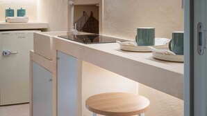 A compact kitchenette with a stove, a small refrigerator, and a bar stool. - Laggetto Corner (Otranto)