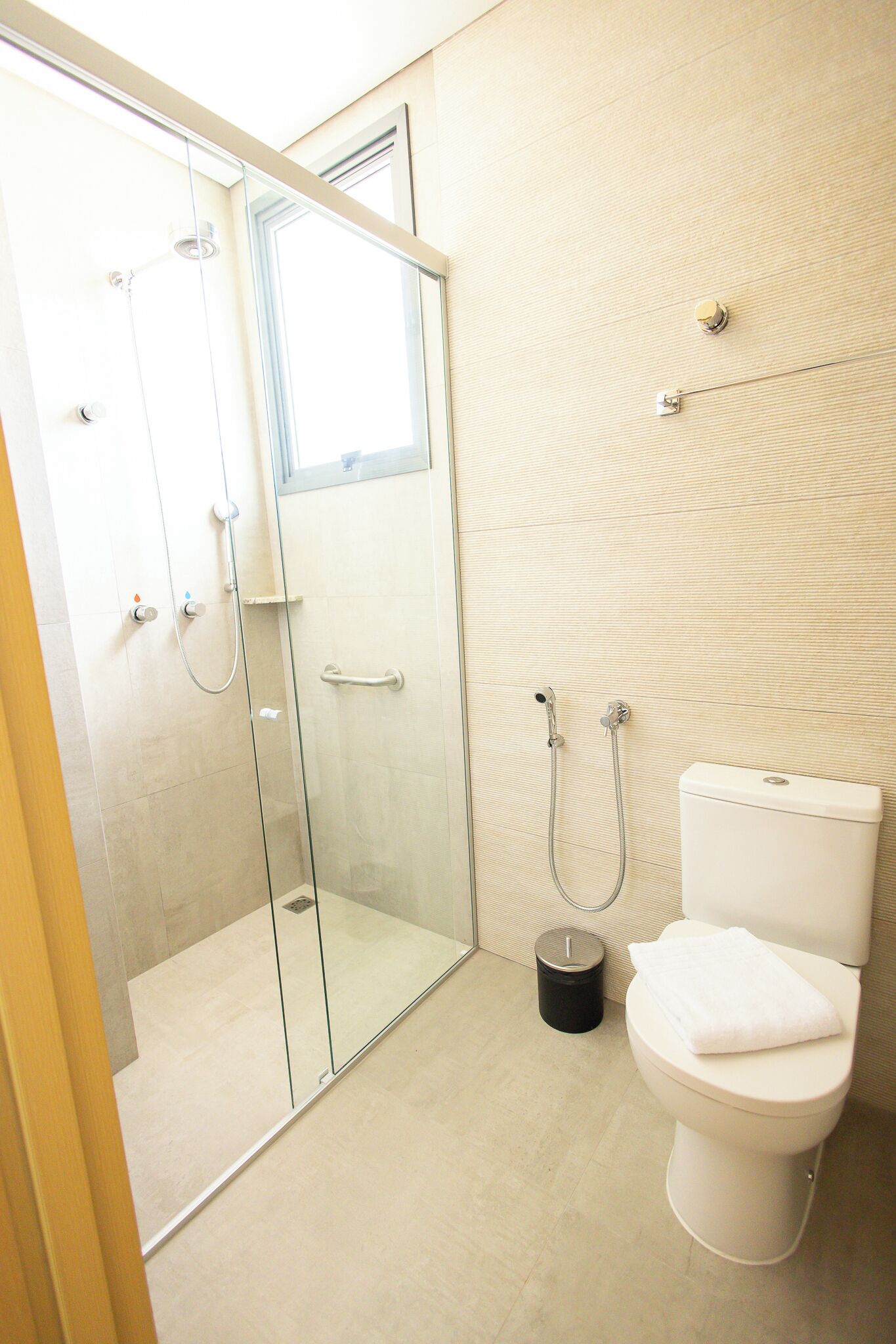 Un baño moderno con cabina de ducha de vidrio, inodoro y un cubo de basura.