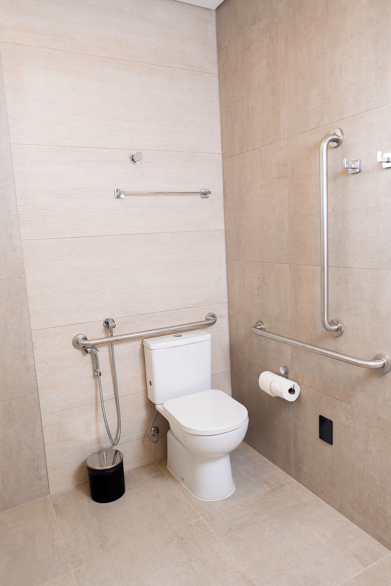 Ein modernes Badezimmer mit Toilette, Handlauf und Haltegriff.