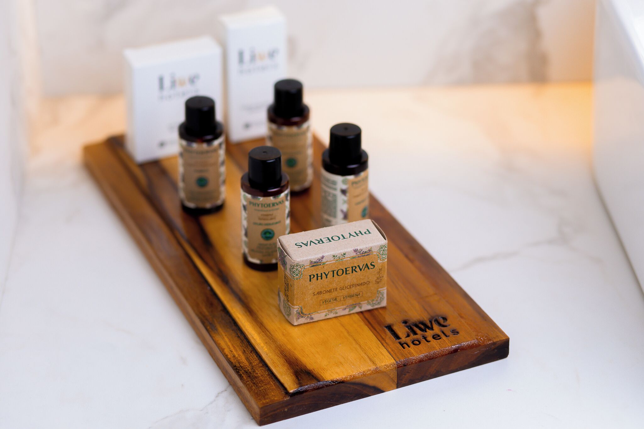 A wooden tray with bottles of PHYOERVAS and a sign labeled "Liu Hotels".