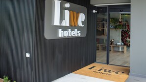 Una entrada de hotel moderna con un letrero que dice "Liwe hotels" y un techo de madera.