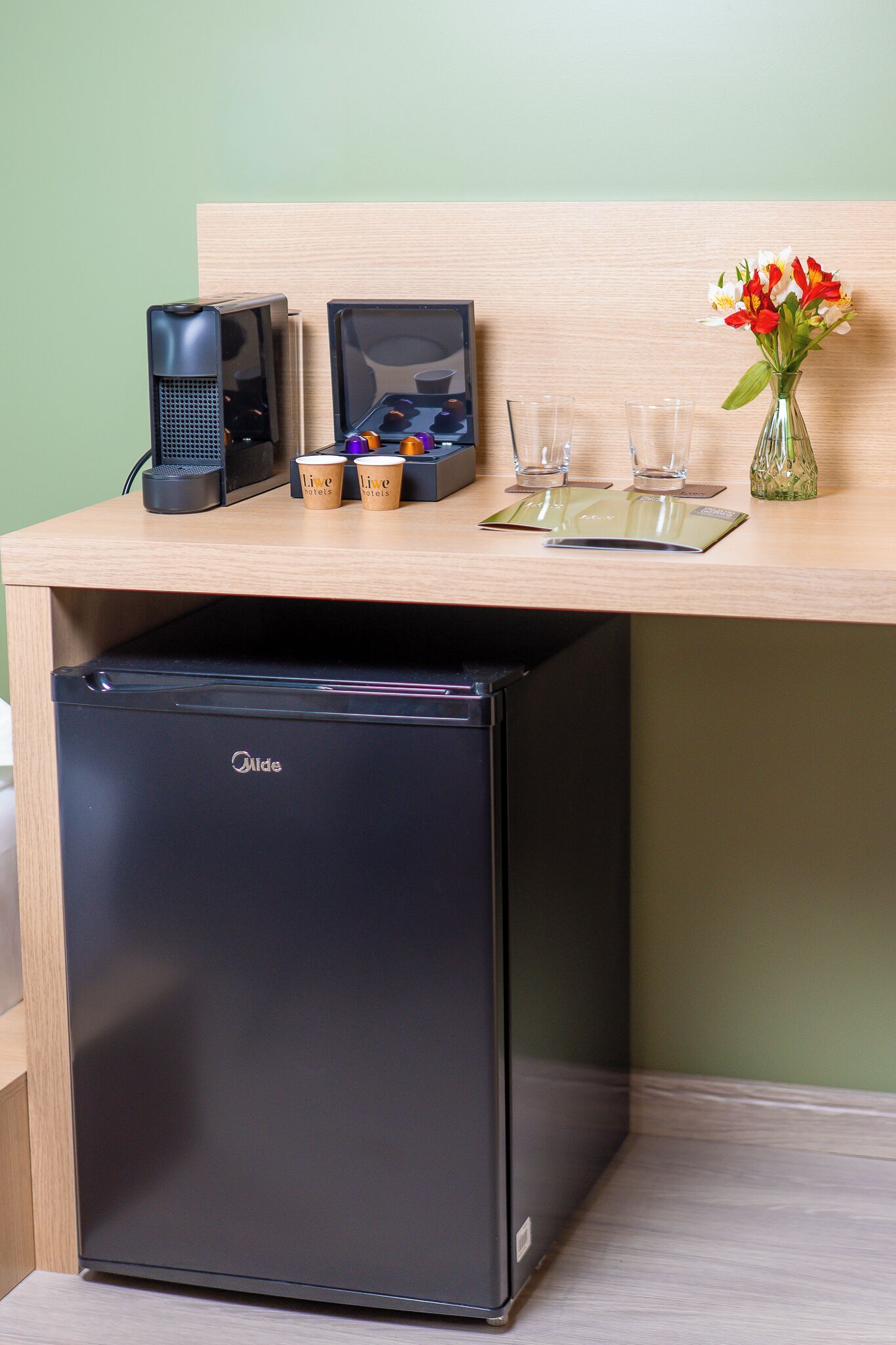 A compact kitchenette with a built-in refrigerator, a coffee machine, and a small sink.
