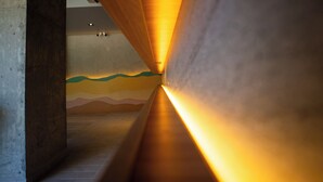 Un pasillo con techo de listones de madera y un mural en la pared.