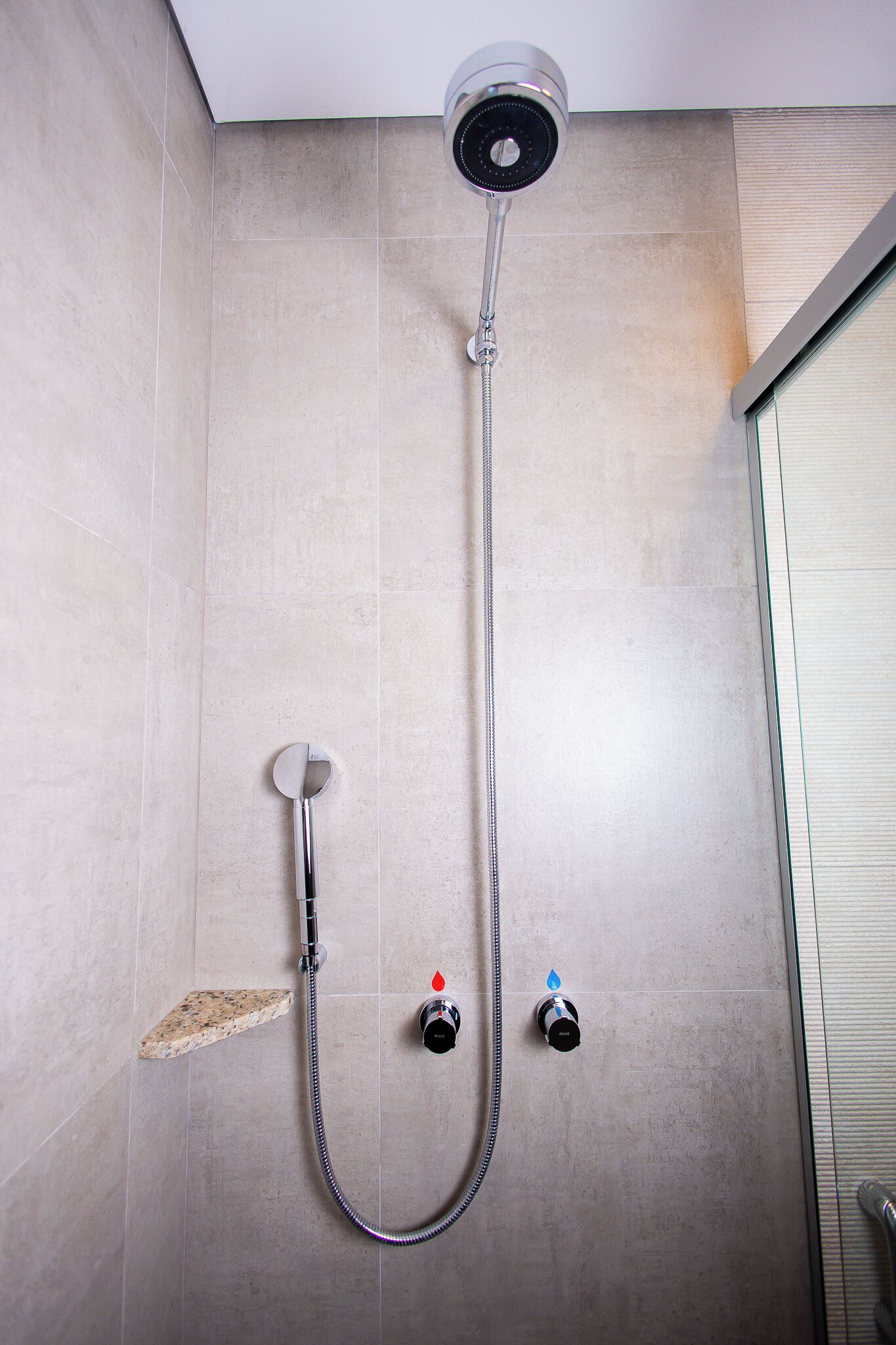 A shower with a handheld showerhead, a handheld shower nozzle, and a wall-mounted control valve.