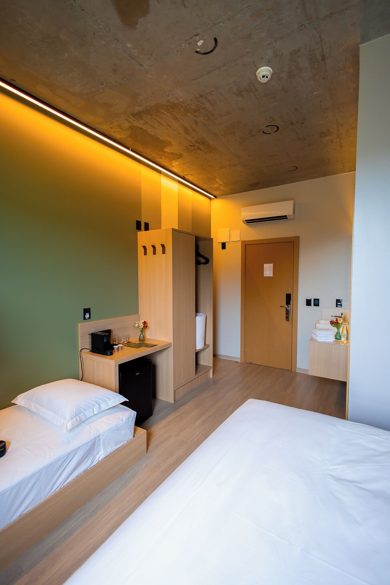 A hotel room with a bed, a desk with a computer, and a small cabinet.