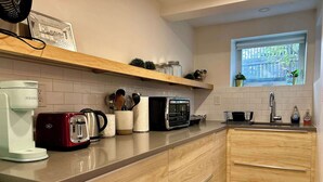 A modern kitchen with a wooden countertop, a coffee maker, a toaster, a microwave, and a window with a view of greenery.