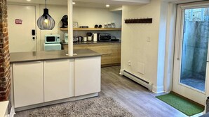 A modern kitchen with white cabinets, a central island, and a dining area with a glass door leading outside.