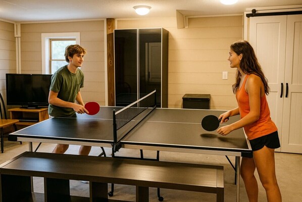 A ping pong table in a room with a TV, cabinets, and a window.