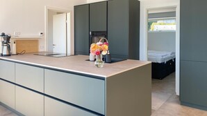 Una cocina moderna con una isla central, horno empotrado y un pequeño comedor.